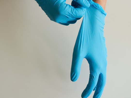 Hände mit blauen Desinfektionshandschuhen
