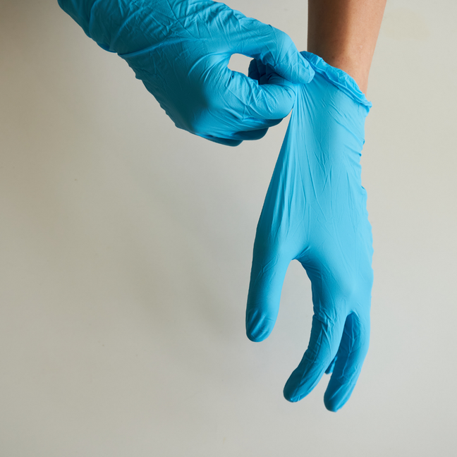 Hände mit blauen Desinfektionshandschuhen