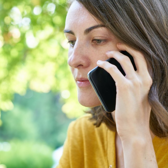Eine ernst blickende Frau telefoniert.