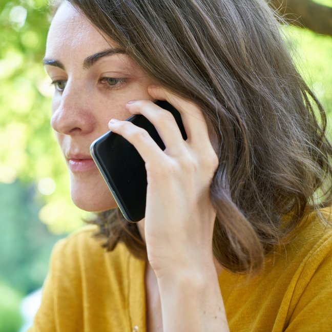 Eine ernst blickende Frau telefoniert.