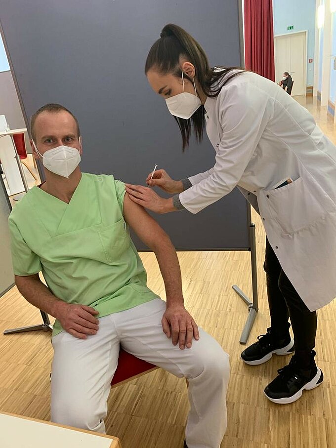 Covid-19-Impfung am kbo-Inn-Salzach-Klinikum Eine Ärztin impft einen Pfleger. Beide tragen FFP2-Masken.
