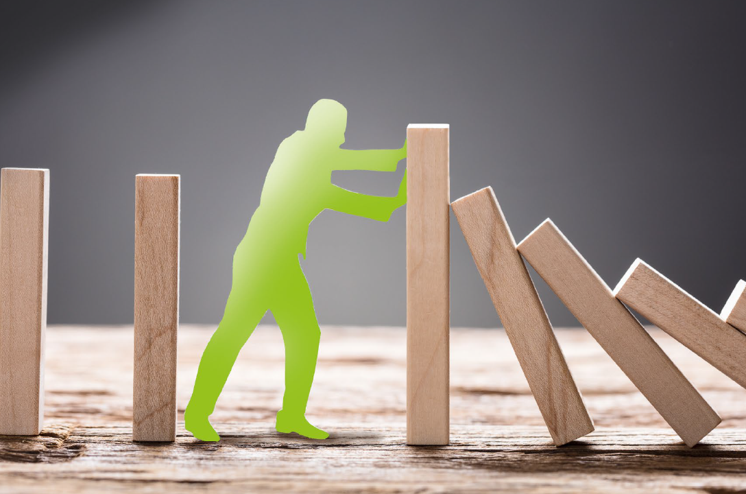 Ein Mann hält fallende Dominosteine auf